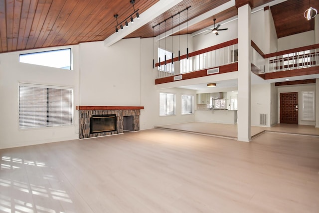 unfurnished living room featuring a wealth of natural light, ceiling fan, wooden ceiling, and a high ceiling