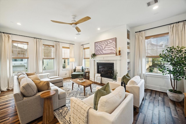 living room with dark hardwood / wood-style floors, ceiling fan, built in features, and a tiled fireplace