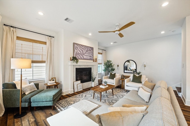 living room featuring plenty of natural light, ceiling fan, dark wood-type flooring, and a tile fireplace