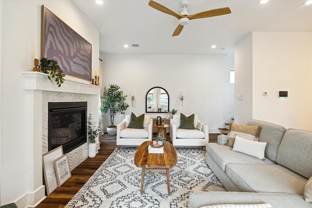 living room featuring dark hardwood / wood-style floors, ceiling fan, and a tiled fireplace