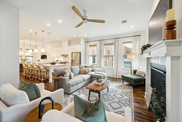 living room featuring ceiling fan, a high end fireplace, and dark hardwood / wood-style floors