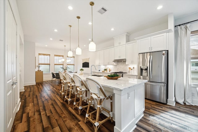 kitchen featuring a healthy amount of sunlight, white cabinetry, a center island with sink, and stainless steel appliances