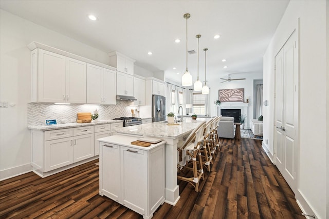 kitchen featuring a kitchen island with sink, white cabinets, and stainless steel appliances