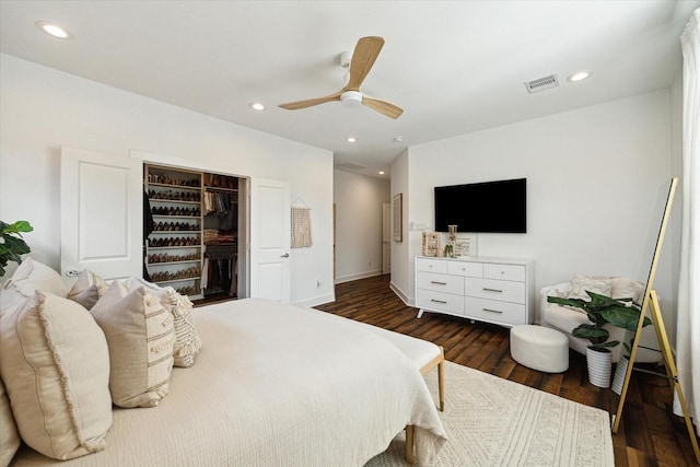 bedroom featuring a walk in closet, dark hardwood / wood-style flooring, a closet, and ceiling fan