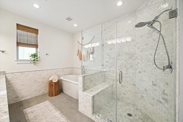 bathroom featuring tile walls and independent shower and bath