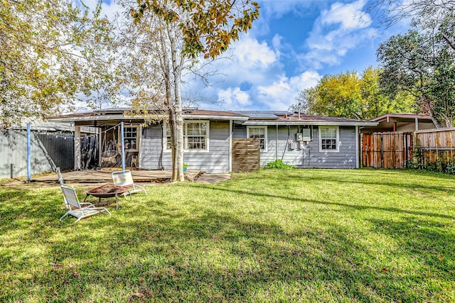 back of property featuring a lawn, an outdoor fire pit, and solar panels