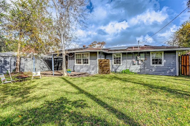 back of property featuring solar panels and a lawn