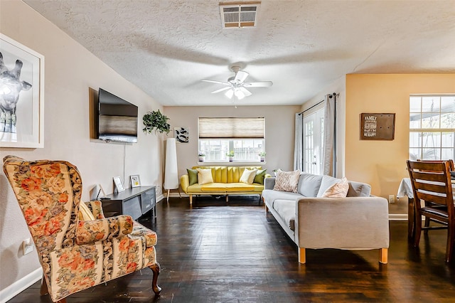 living room featuring ceiling fan, dark wood-type flooring, and a textured ceiling