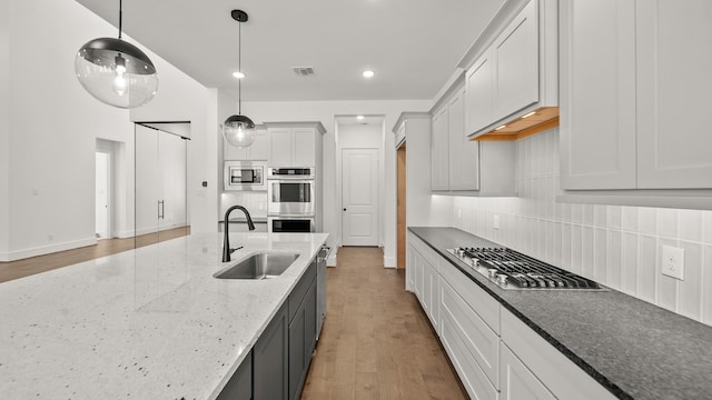 kitchen featuring decorative light fixtures, white cabinetry, hardwood / wood-style flooring, and sink