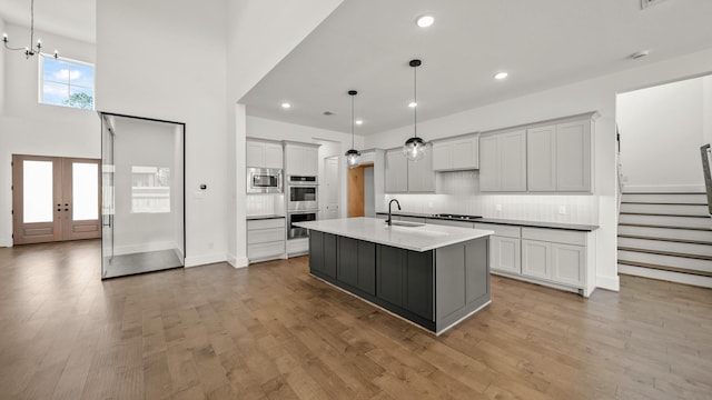 kitchen featuring pendant lighting, a center island with sink, light hardwood / wood-style flooring, and sink