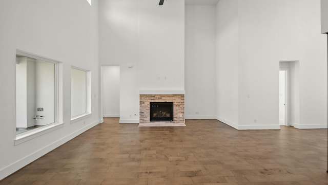 unfurnished living room with hardwood / wood-style flooring, a towering ceiling, and a fireplace