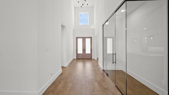 entrance foyer featuring light hardwood / wood-style flooring, a chandelier, and a high ceiling