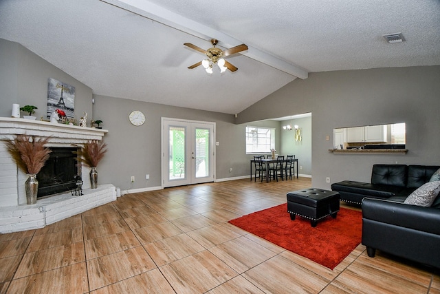 living room featuring ceiling fan, lofted ceiling with beams, a textured ceiling, a fireplace, and light tile patterned floors