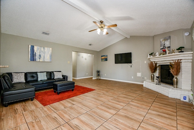 living room with ceiling fan, a brick fireplace, vaulted ceiling with beams, a textured ceiling, and light tile patterned flooring