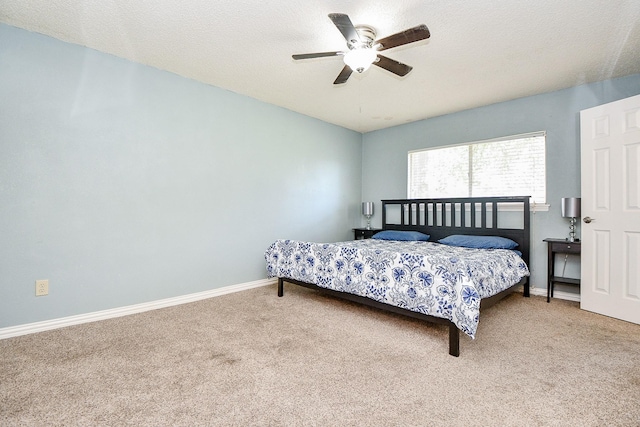 carpeted bedroom with ceiling fan and a textured ceiling