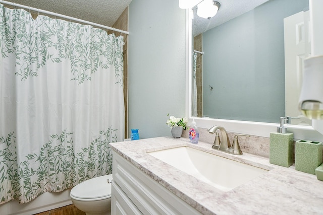 full bathroom with shower / tub combo with curtain, vanity, a textured ceiling, and toilet