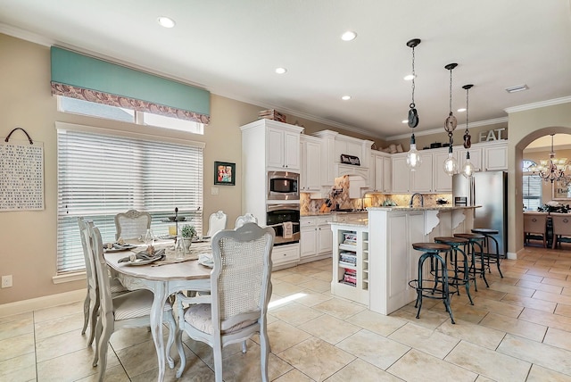 kitchen featuring light stone countertops, appliances with stainless steel finishes, pendant lighting, a center island with sink, and white cabinetry