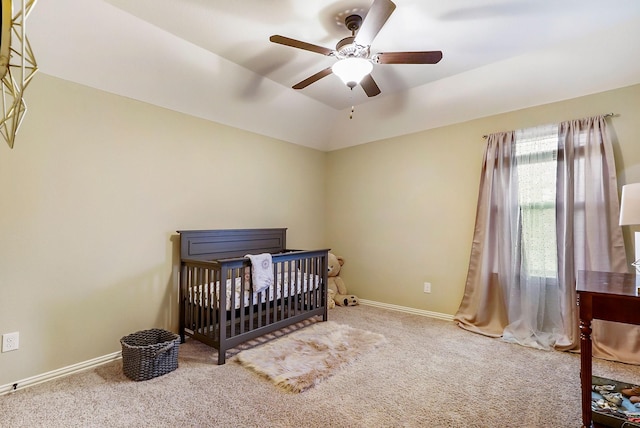 bedroom with ceiling fan, carpet, a nursery area, and vaulted ceiling