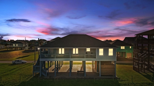 back house at dusk featuring a yard, a patio, and a balcony