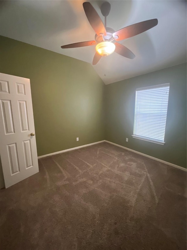 empty room with ceiling fan, dark carpet, and vaulted ceiling