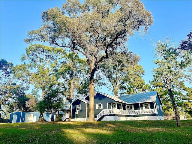 view of front facade featuring covered porch, an outbuilding, and a front yard