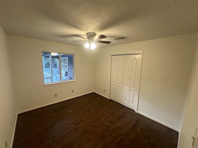 unfurnished bedroom with a textured ceiling, dark hardwood / wood-style flooring, a closet, and ceiling fan