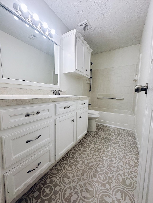 full bathroom featuring vanity, toilet, a textured ceiling, and tiled shower / bath