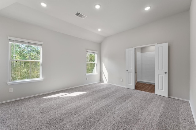 empty room with lofted ceiling and dark colored carpet