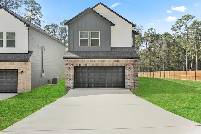 view of front facade with a front yard, central AC unit, and a garage