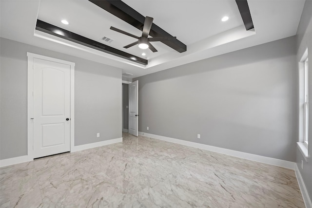 empty room with ceiling fan and a raised ceiling