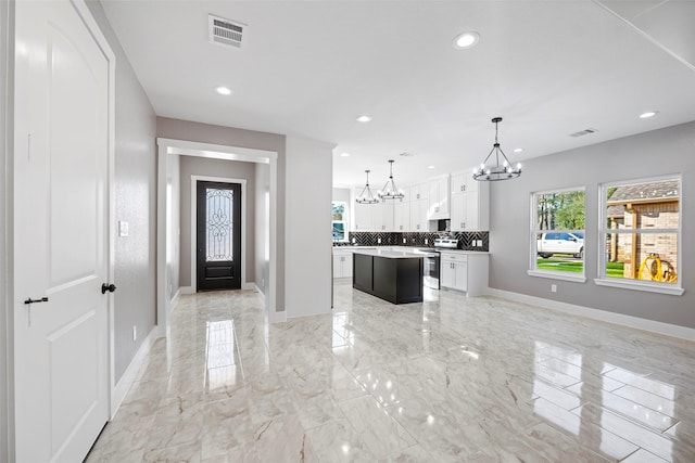 kitchen with backsplash, decorative light fixtures, a center island, white cabinetry, and stainless steel electric range