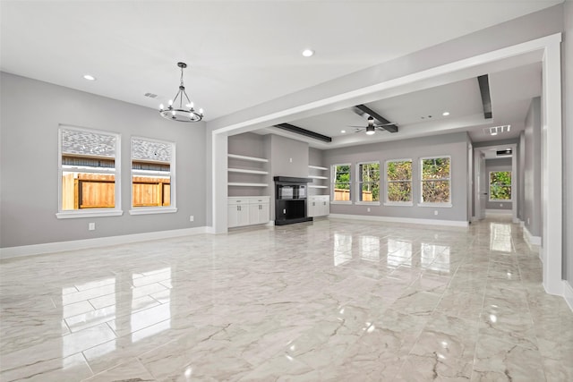 unfurnished living room featuring built in shelves, ceiling fan with notable chandelier, and a raised ceiling