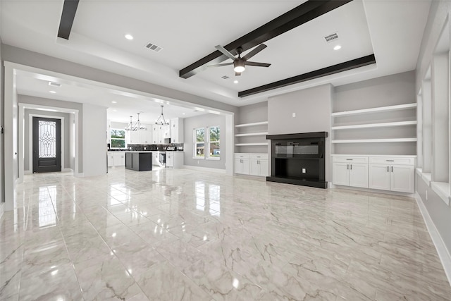 unfurnished living room featuring ceiling fan with notable chandelier and a raised ceiling