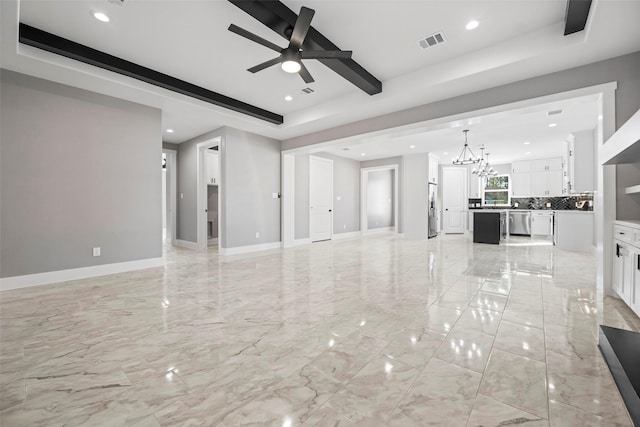 unfurnished living room featuring a tray ceiling and ceiling fan with notable chandelier