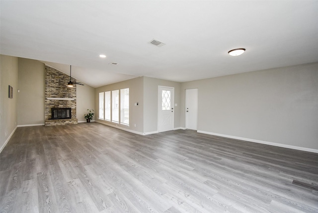 unfurnished living room featuring lofted ceiling, a brick fireplace, hardwood / wood-style flooring, and ceiling fan