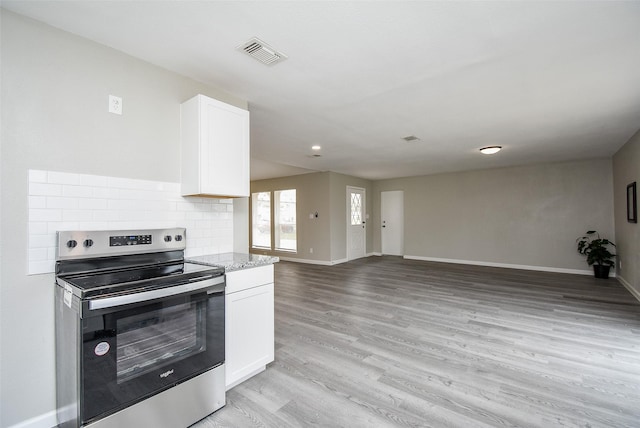 kitchen with light wood-type flooring, electric range, light stone countertops, decorative backsplash, and white cabinets