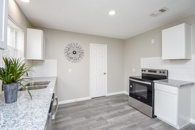 kitchen with sink, white cabinets, light wood-type flooring, and stainless steel electric range