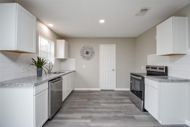 kitchen featuring stainless steel appliances, sink, light hardwood / wood-style flooring, and white cabinets