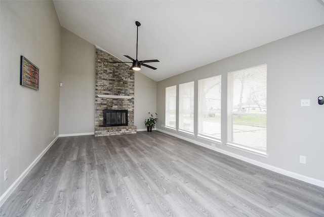 unfurnished living room featuring ceiling fan, high vaulted ceiling, a brick fireplace, and light wood-type flooring