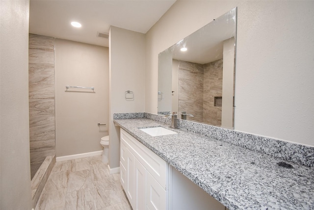 bathroom featuring vanity, tiled shower, and toilet