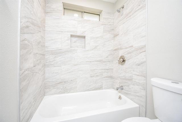 bathroom featuring tiled shower / bath combo and toilet