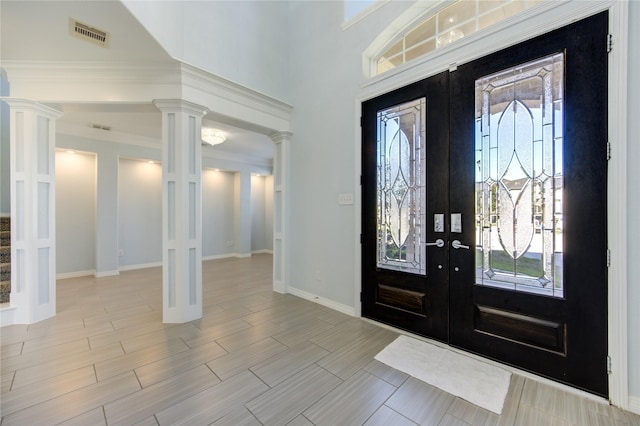 foyer featuring ornate columns, french doors, a towering ceiling, and a healthy amount of sunlight