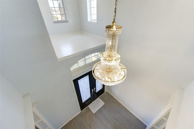 foyer featuring hardwood / wood-style floors, an inviting chandelier, and a high ceiling