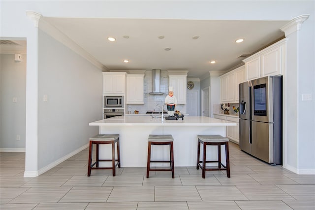 kitchen featuring appliances with stainless steel finishes, backsplash, wall chimney exhaust hood, and an island with sink