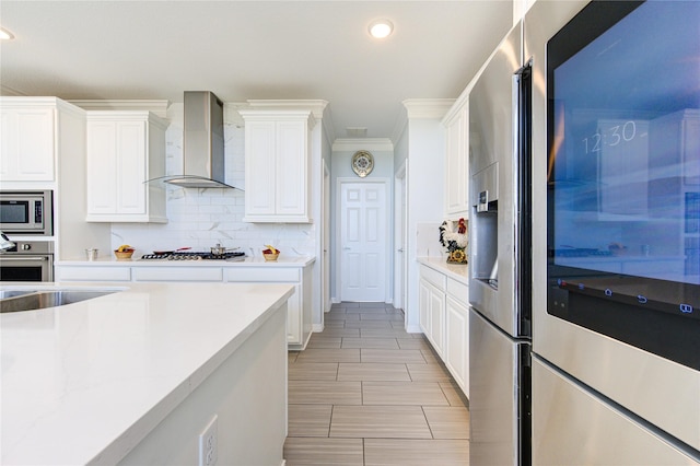 kitchen with white cabinets, appliances with stainless steel finishes, and wall chimney exhaust hood