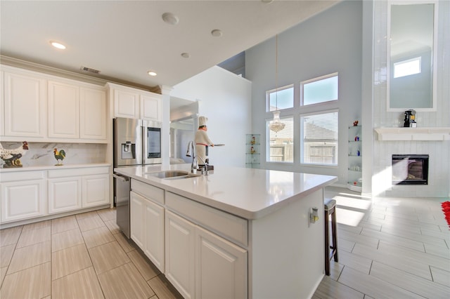 kitchen with a wealth of natural light, white cabinetry, sink, and an island with sink