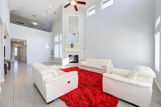 living room featuring ceiling fan, a healthy amount of sunlight, and a high ceiling