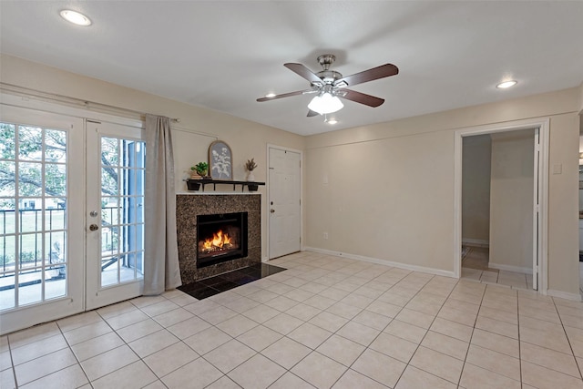 unfurnished living room with a tiled fireplace, ceiling fan, french doors, and light tile patterned floors