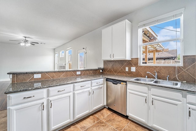 kitchen featuring white cabinetry, stainless steel dishwasher, sink, kitchen peninsula, and dark stone counters