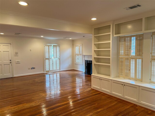 unfurnished living room with built in features, dark wood-type flooring, and ornamental molding